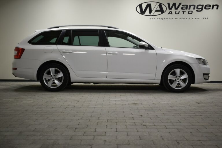 A white station wagon is parked indoors on a tiled floor, with a logo and website on the wall in the background.