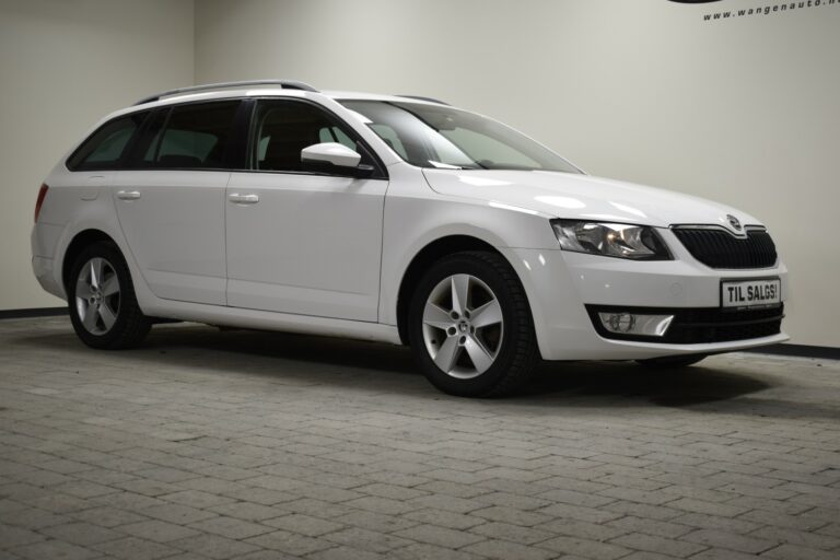 A white station wagon is parked indoors on a gray tiled floor, with lighting highlighting its features.