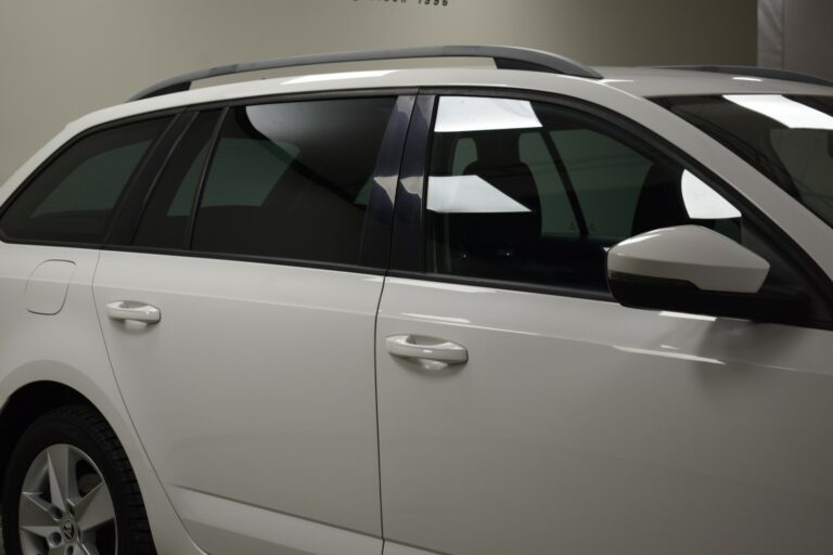 Side view of a white car, focusing on the rear passenger door and part of the front door, with dark-tinted windows and a roof rack.