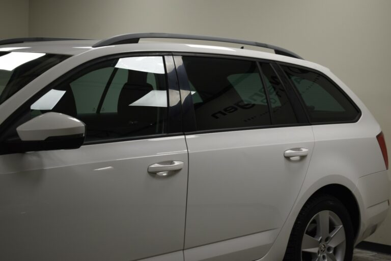 Side view of a white car parked indoors, showing the rear passenger door and tinted windows.