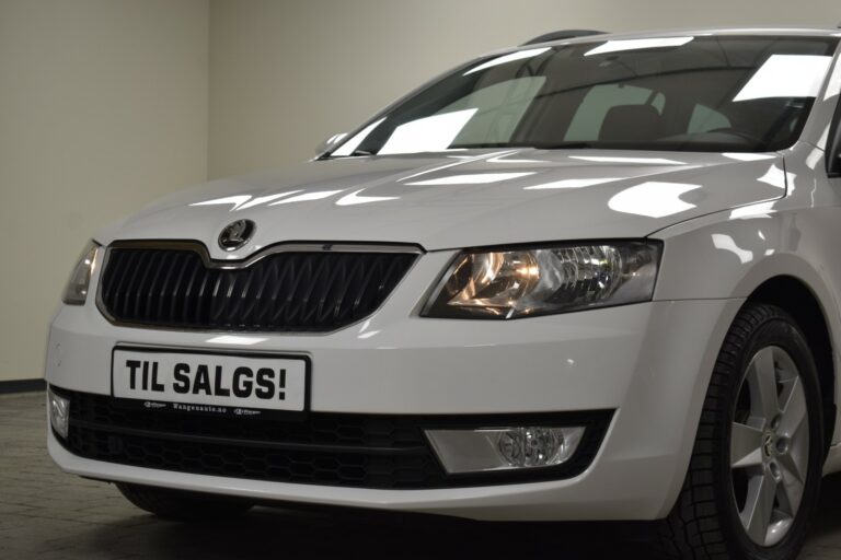 White car on display indoors with a front license plate reading "TIL SALGS!" which means "FOR SALE" in Norwegian.