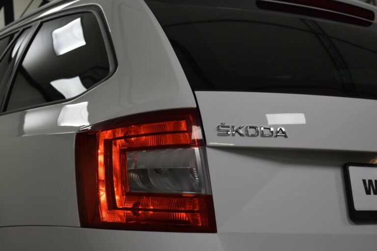 Close-up of a white Škoda car's rear, focusing on the taillight and Škoda logo.