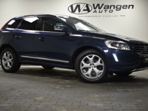 Dark blue Volvo SUV parked indoors at Wangen Auto, side view. Logo and website visible on the wall behind the vehicle.