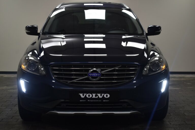 Front view of a dark-colored Volvo SUV with headlights on, displayed indoors.