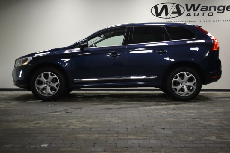 Side view of a blue SUV parked indoors on a tiled floor, with a company logo visible on the wall in the background.