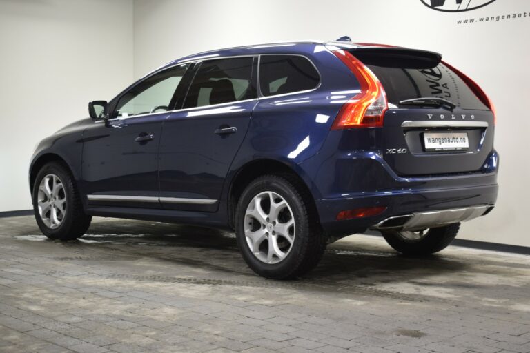 A blue Volvo XC60 parked indoors on a tiled floor, viewed from the rear three-quarter angle.