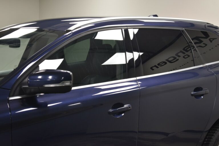 Close-up of a blue SUV showing the side view, focusing on the windows, side mirror, and door handle under bright indoor lighting.