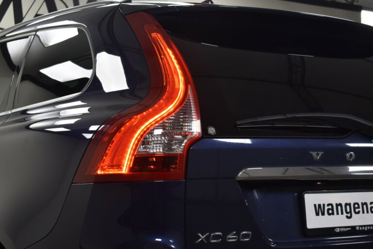 Close-up of a blue Volvo XC60's rear, highlighting the taillight and logo.