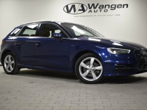 A blue Audi hatchback parked indoors on a tiled floor with a Wangen Auto sign in the background.