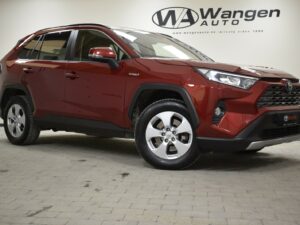 Red SUV parked indoors, displaying alloy wheels and hybrid badge, with "Wangen Auto" logo on wall in the background.