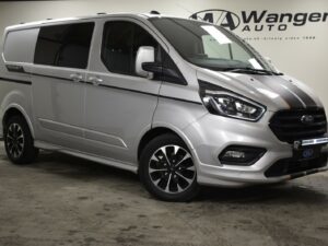 Silver van with black wheels and orange accents parked indoors. Wangen Auto signage in the background.