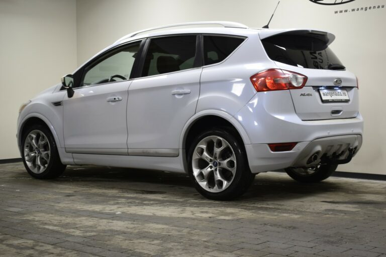 White SUV parked indoors, rear and side view, showcasing alloy wheels and a visible license plate area.