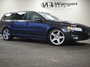 A dark blue station wagon with silver alloy wheels is parked indoors on a tiled floor.